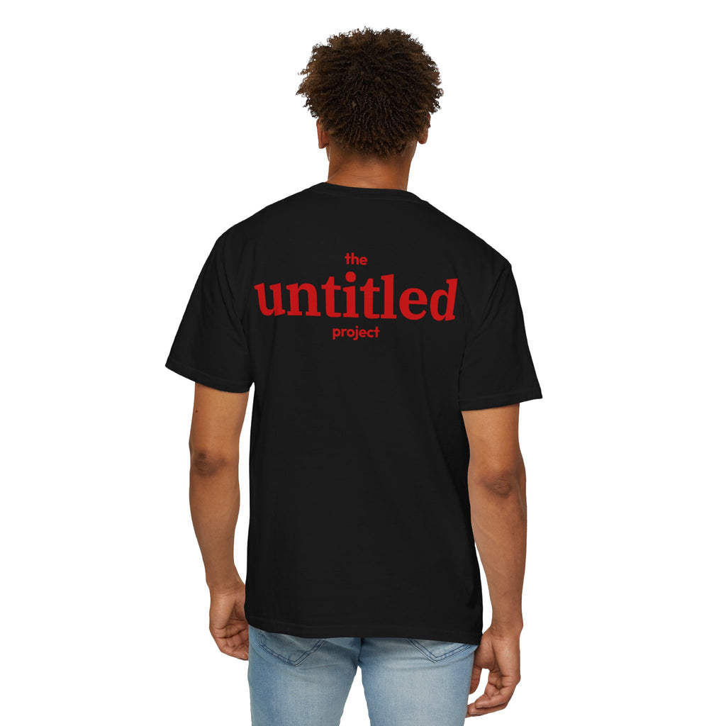 Person wearing Black comfort color 1717 zeromode t-shirt with "the untitled project" text on the back in red color.