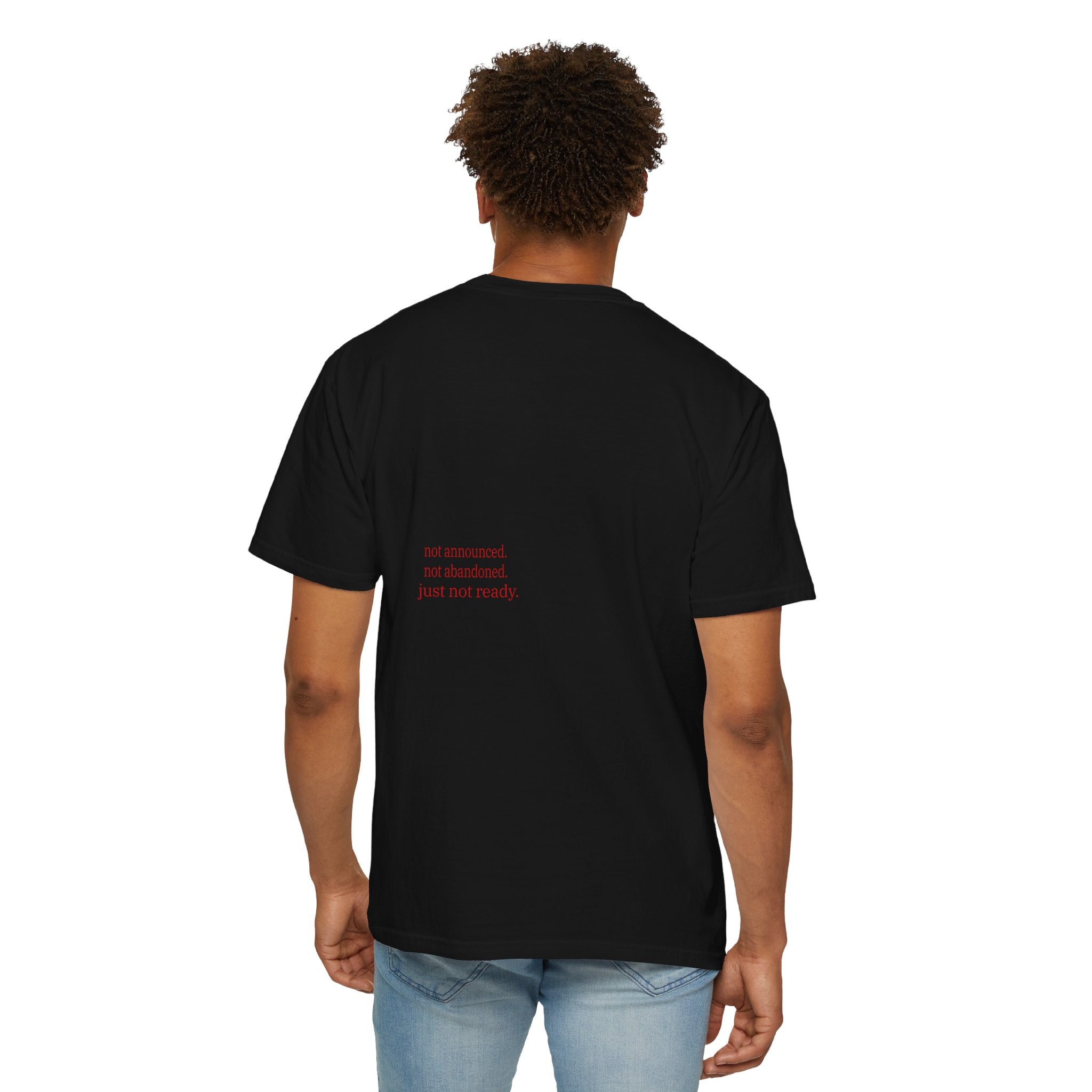 Person wearing a Black t-shirt with red text on the back, standing against a white background