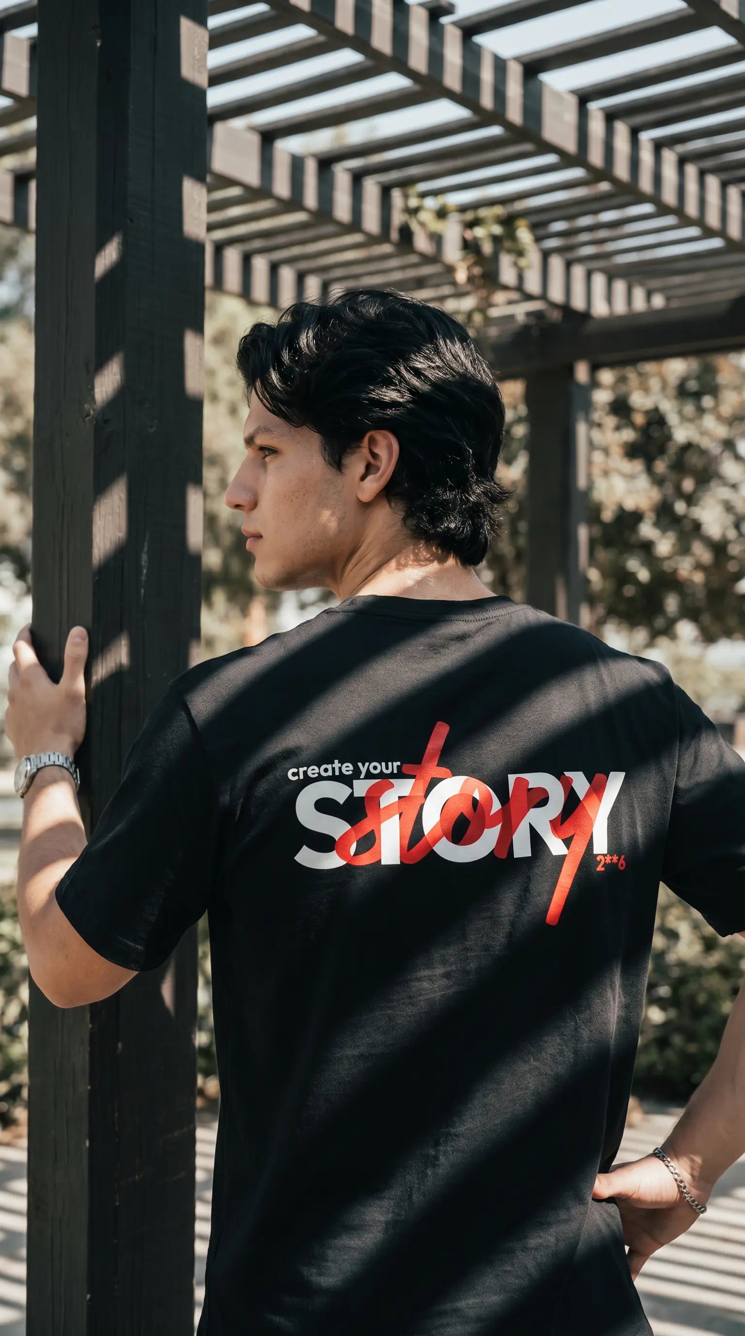 Person wearing a black t-shirt with 'create your story' text, standing outdoors.