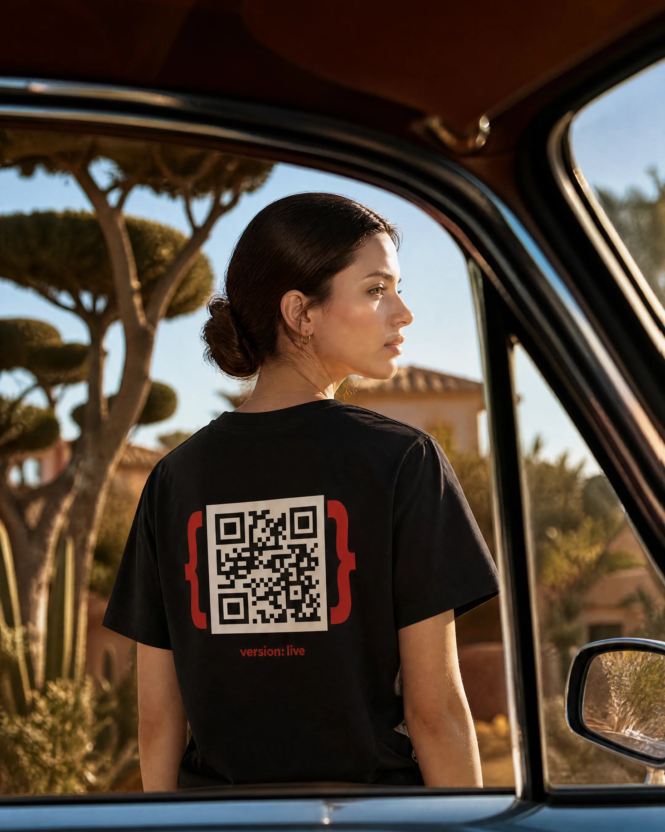 Woman wearing a black t-shirt with a QR code design, standing inside a vehicle.