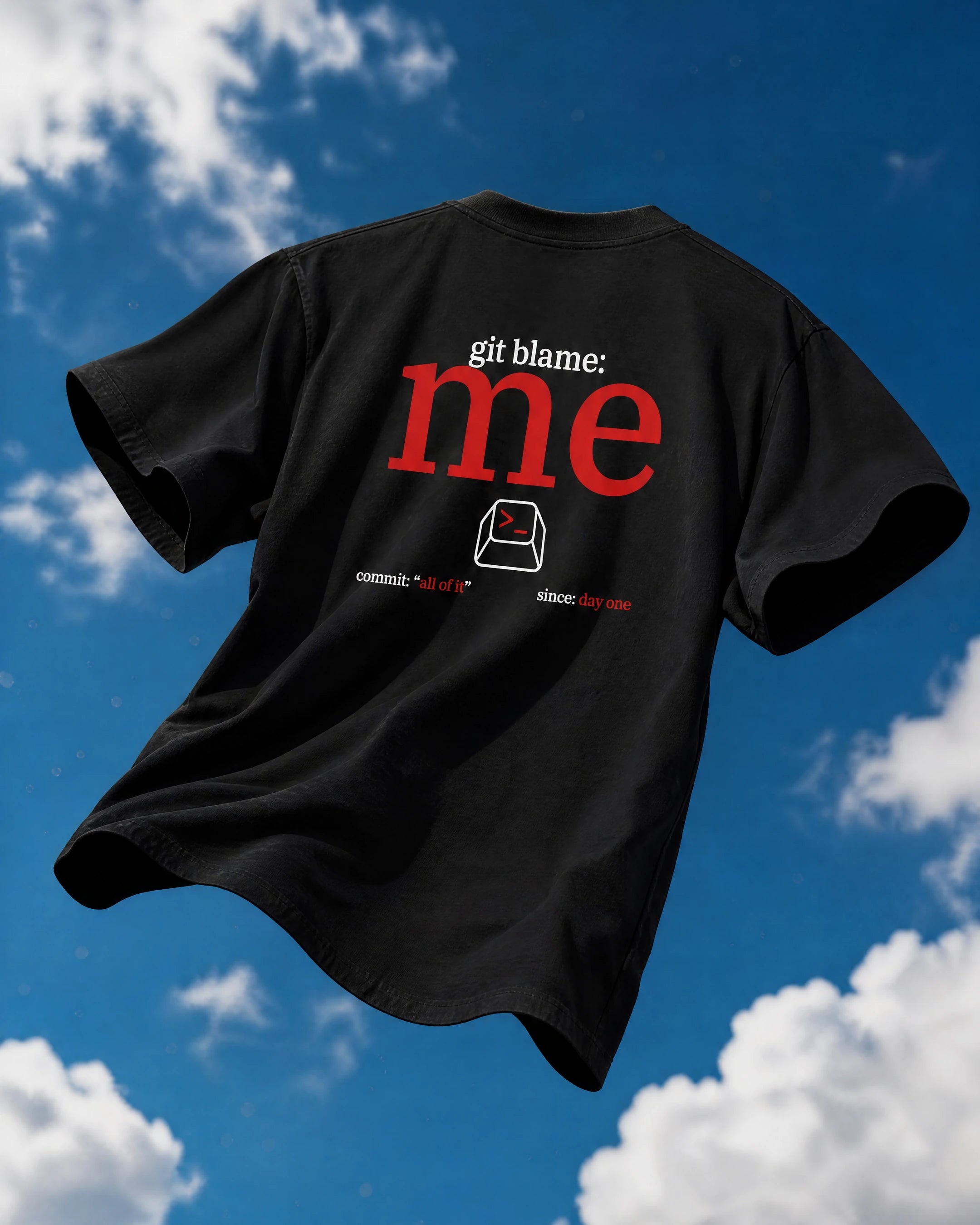 A black short-sleeve T-shirt shown from the back, floating against a blue sky with white clouds. The shirt features a graphic print reading 'git blame: me' in red and white text with a small red-and-black icon below.