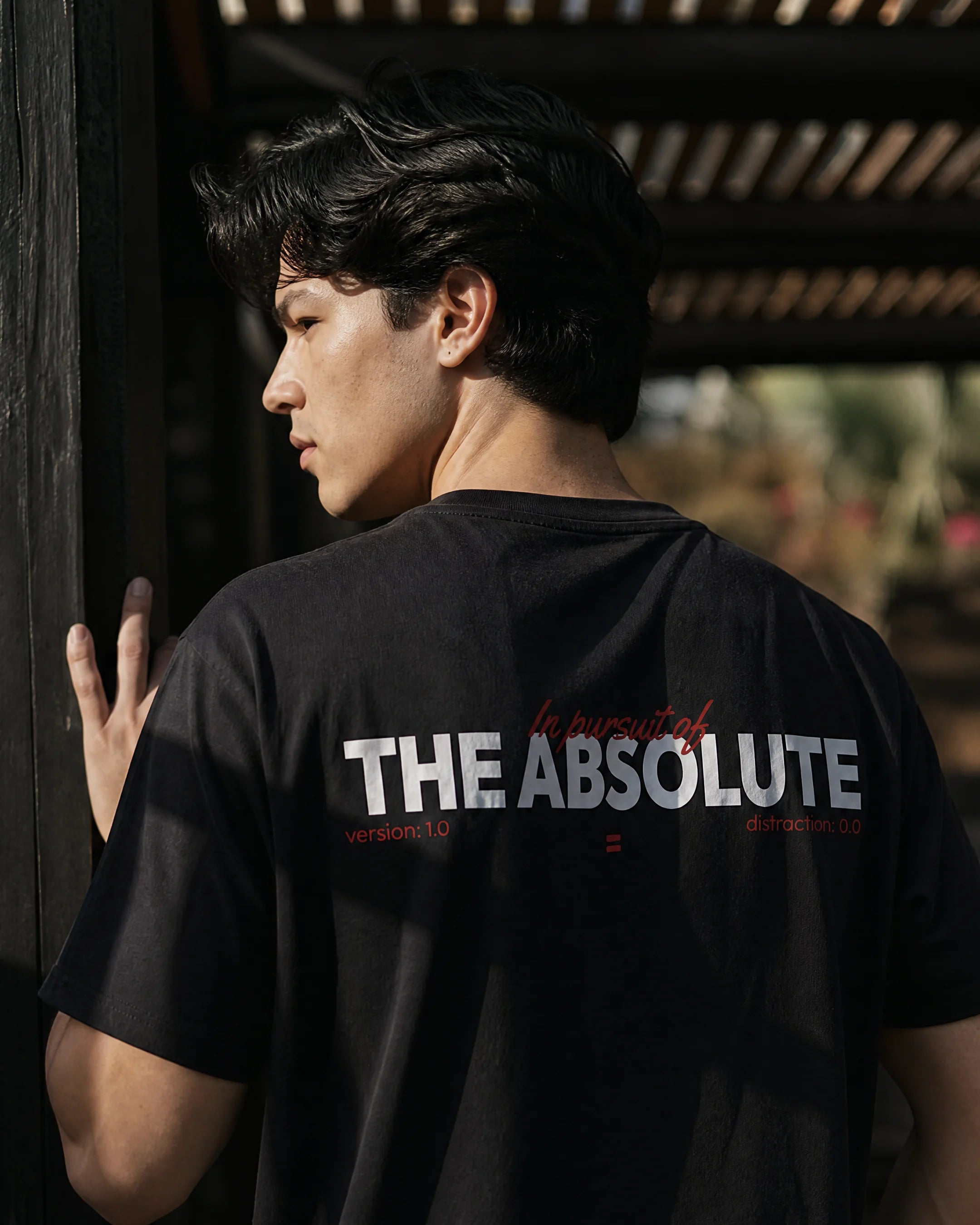 Person wearing a black t-shirt with 'THE ABSOLUTE' text, standing indoors.