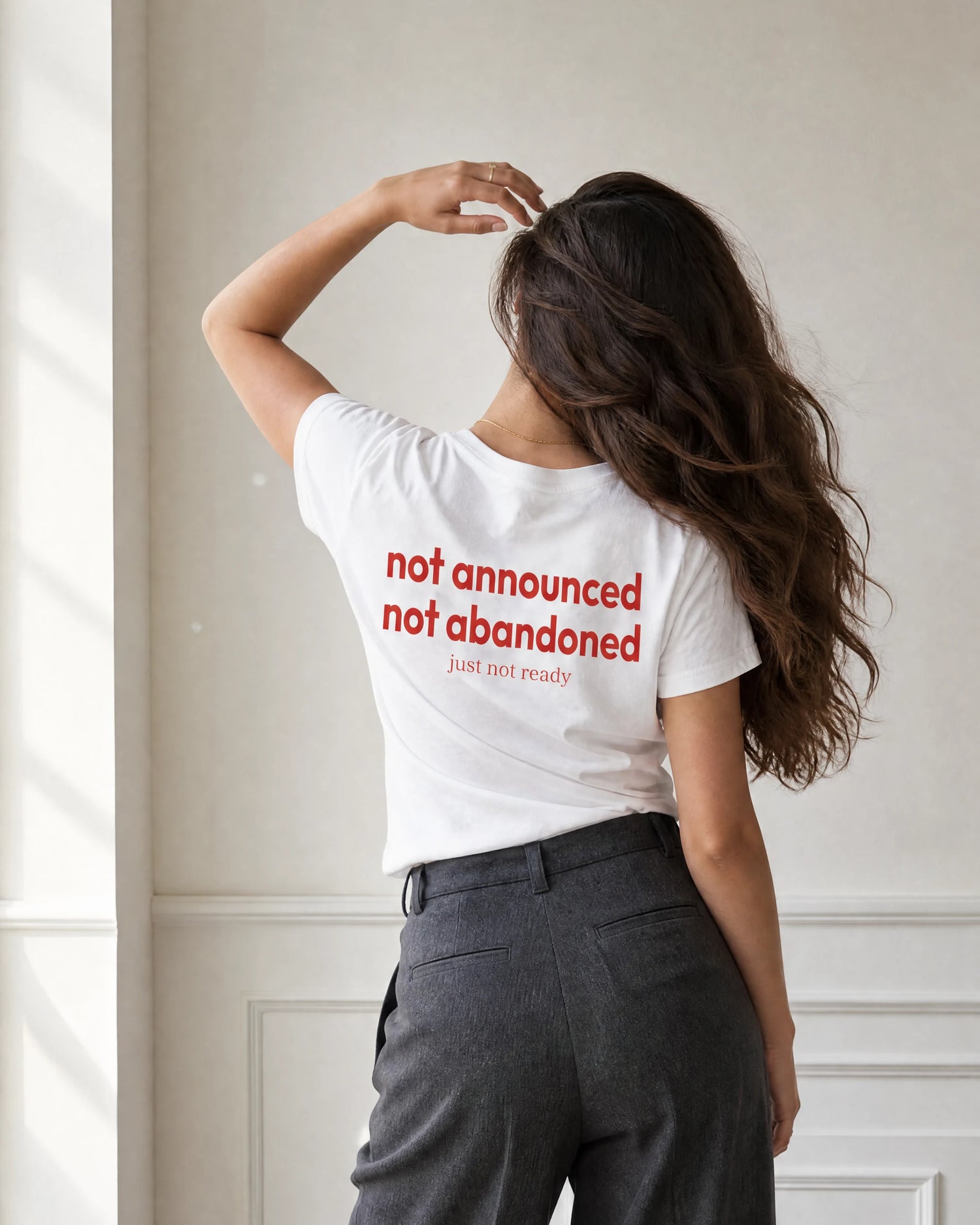 Zehra wearing a white quiet t-shirt with red text in a neutral setting